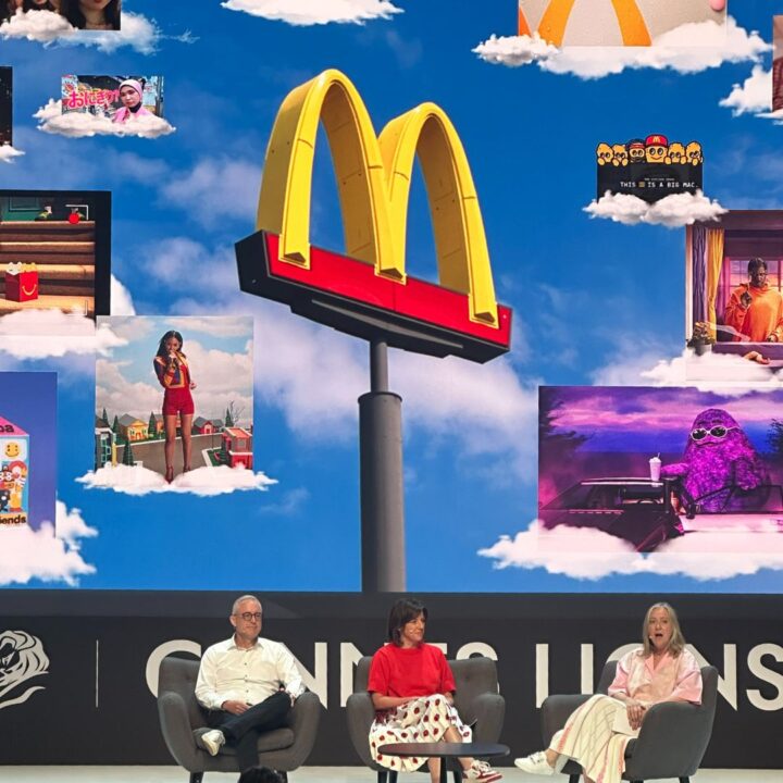 3 people sitting on stage with screen in background showing McDonalds Golden Arches M logo and other graphics