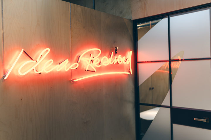 Neon orange sign that says "ideas realised"