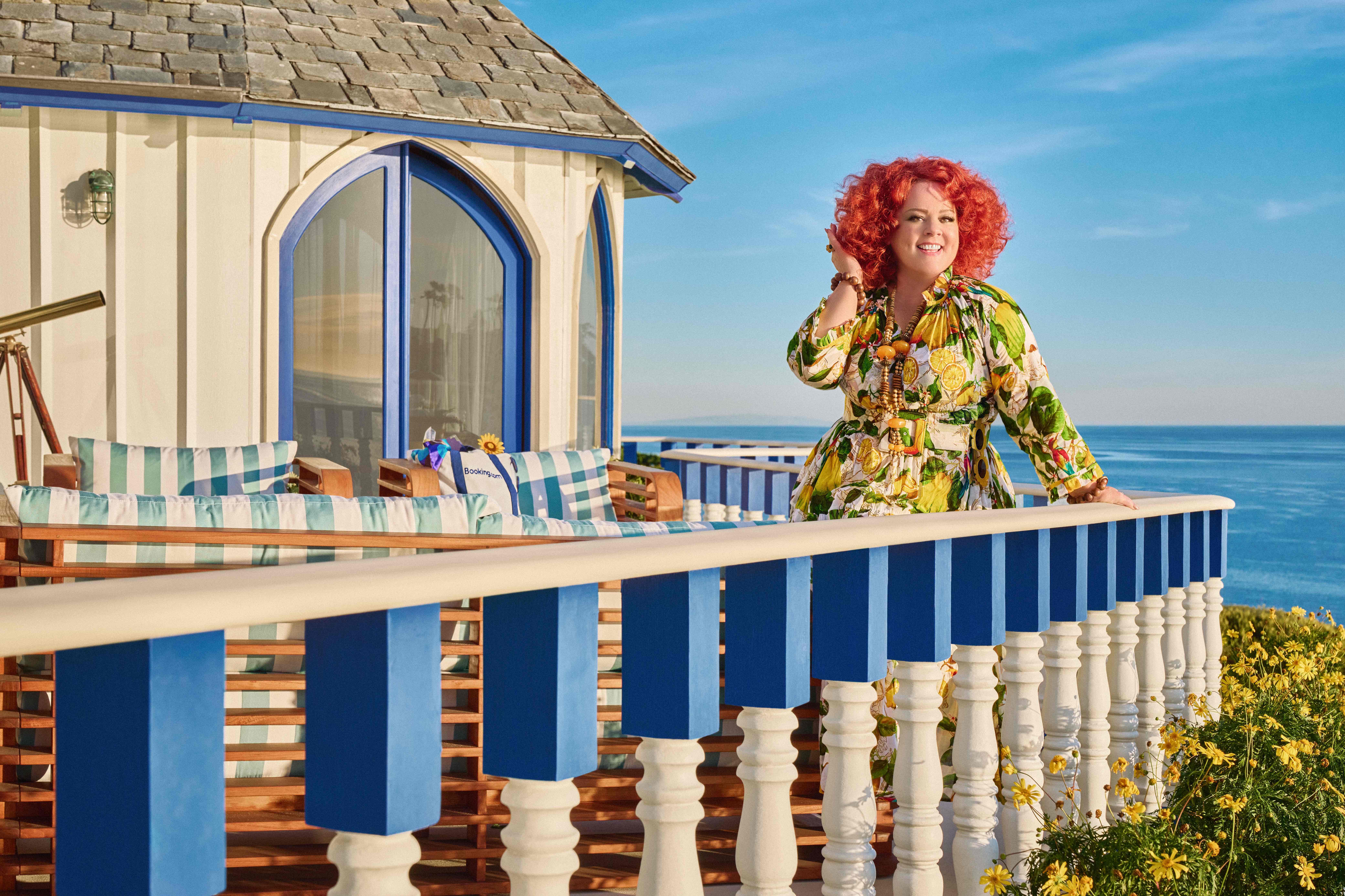 Melissa McCarthy in summer clothes, standing on a balcony of beautiful hotel on holiday.